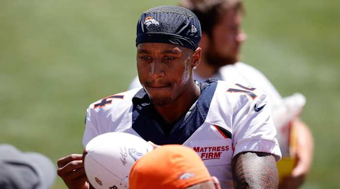 Broncos receiver Courtland Sutton signs a football for a fan during training camp